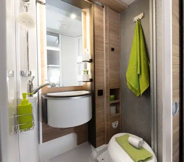 Badezimmer im Dethleffs Globebus Performance 4x4 mit Waschbecken, Spiegel, Toilette und grünen Handtüchern