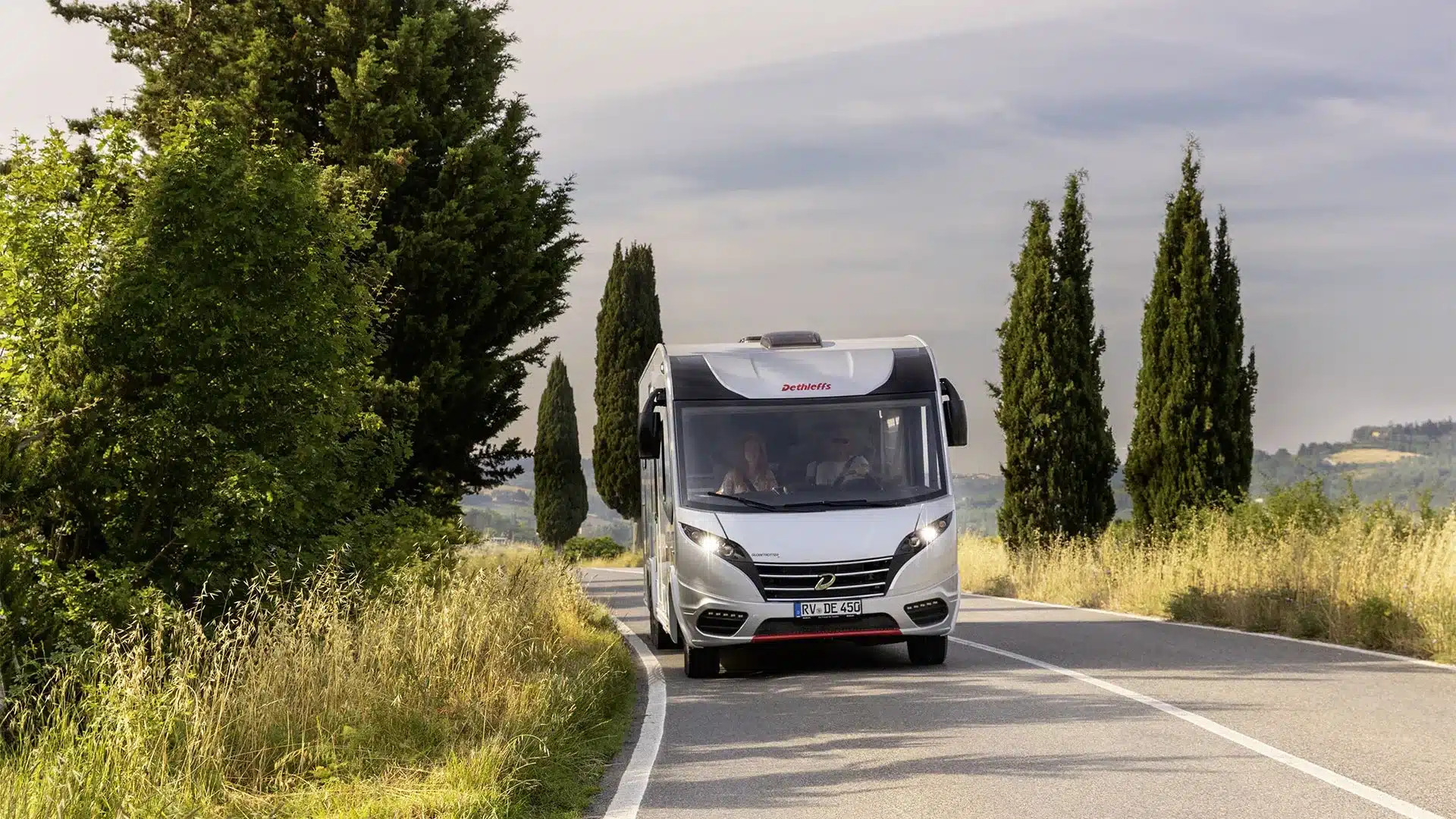Dethleffs Globetrotter XL I fährt auf einer von Bäumen gesäumten Landstraße