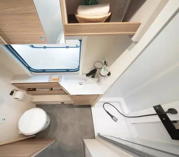 Badezimmer im Dethleffs Nomad Wohnwagen mit Dusche, Toilette, Waschbecken und Holzdekor