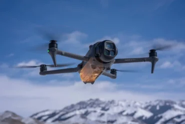 DJI Mavic 4 Pro Drohne fliegt vor verschneiten Bergen und blauem Himmel