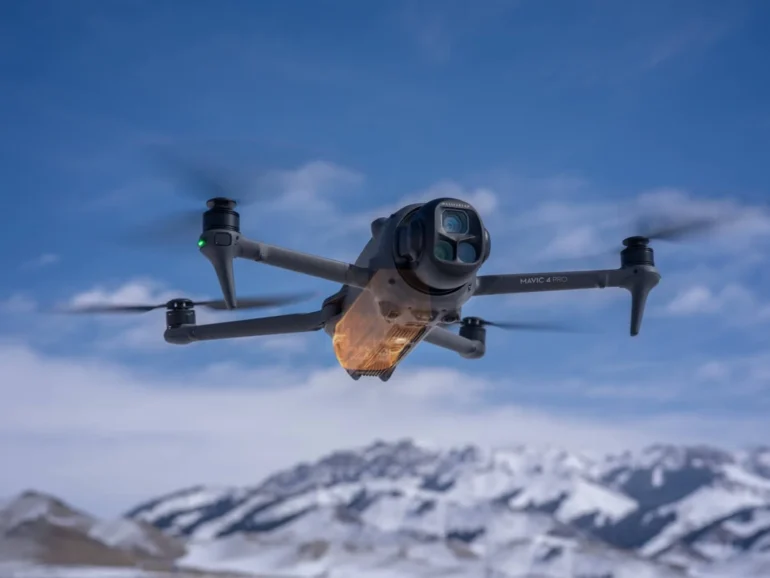 DJI Mavic 4 Pro Drohne fliegt vor verschneiten Bergen und blauem Himmel
