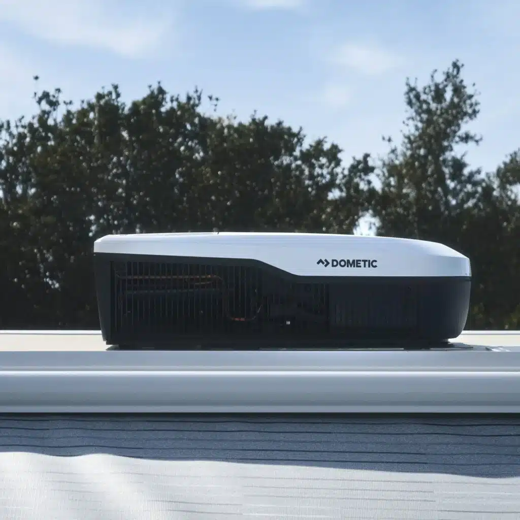 Dometic FreshJet FJX4 2200 Dachklimaanlage montiert auf dem Dach eines Wohnmobils vor Bäumen und blauem Himmel