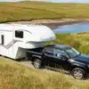 Dreamseeker Fifth Wheel Caravan wird von einem schwarzen Pick-up auf einer Landstraße in einer grünen Landschaft gezogen