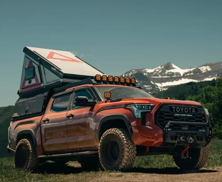 Pickup mit DWELL SHELL Hartschalen-Truck-Camper und aufgeklapptem Origami-Dach vor Bergkulisse