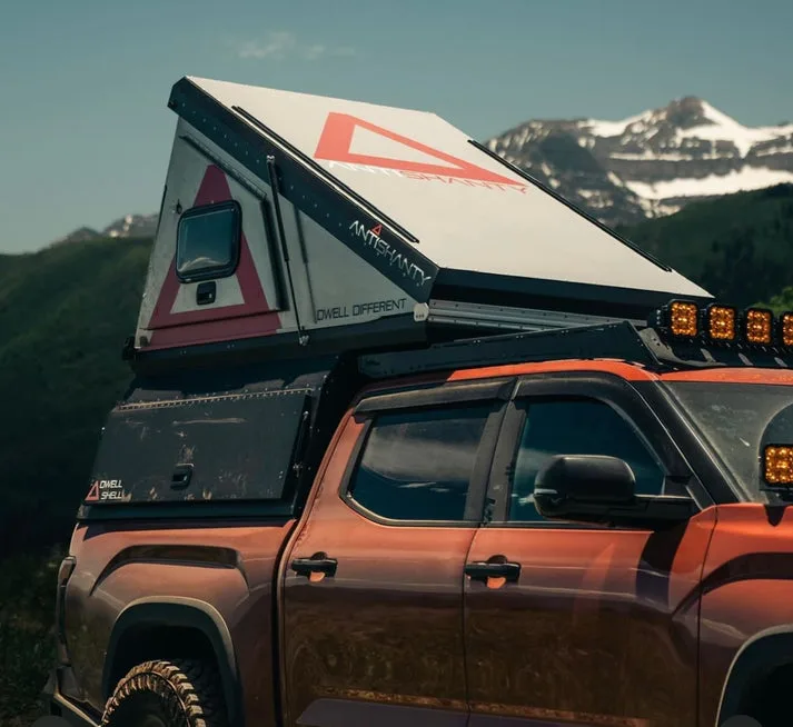 Pickup mit aufgebautem DWELL SHELL Hartschalen-Camper vor Bergkulisse