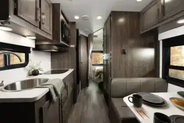 Innenansicht des Entegra Coach Esteem XL mit Küchenzeile, Spüle, Mikrowelle, Sitzgruppe und Blick ins Schlafzimmer