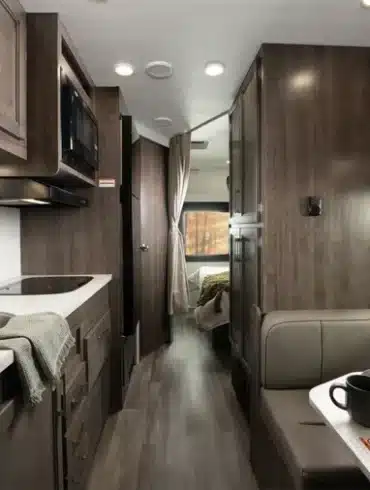 Innenansicht des Entegra Coach Esteem XL mit Küchenzeile, Spüle, Mikrowelle, Sitzgruppe und Blick ins Schlafzimmer