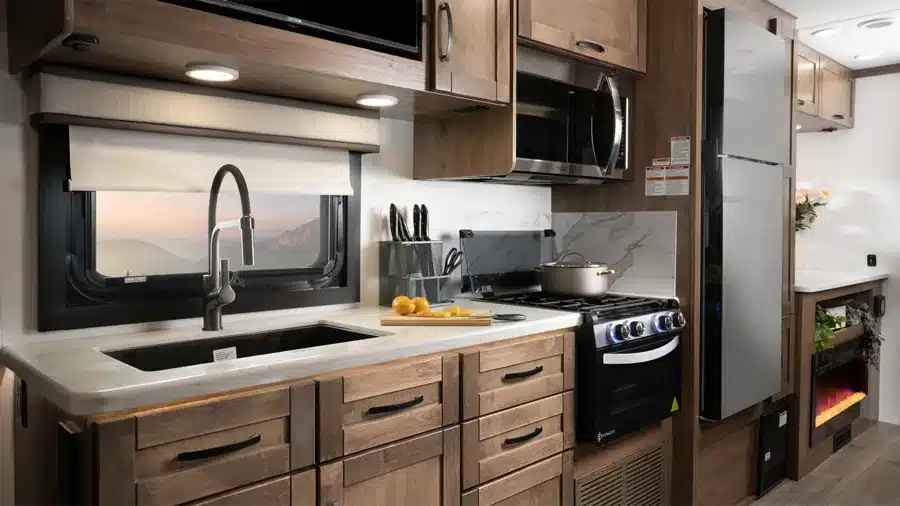 Innenansicht der Küche im Entegra Coach Esteem XL mit Spüle, Herd, Mikrowelle und Kühlschrank