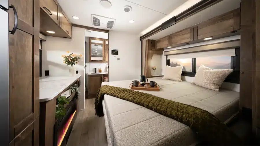 Hochwertig ausgestatteter Innenraum eines Entegra Coach Esteem XL Super-C-Reisemobils mit großem Bett, Holzschränken und Panoramafenster