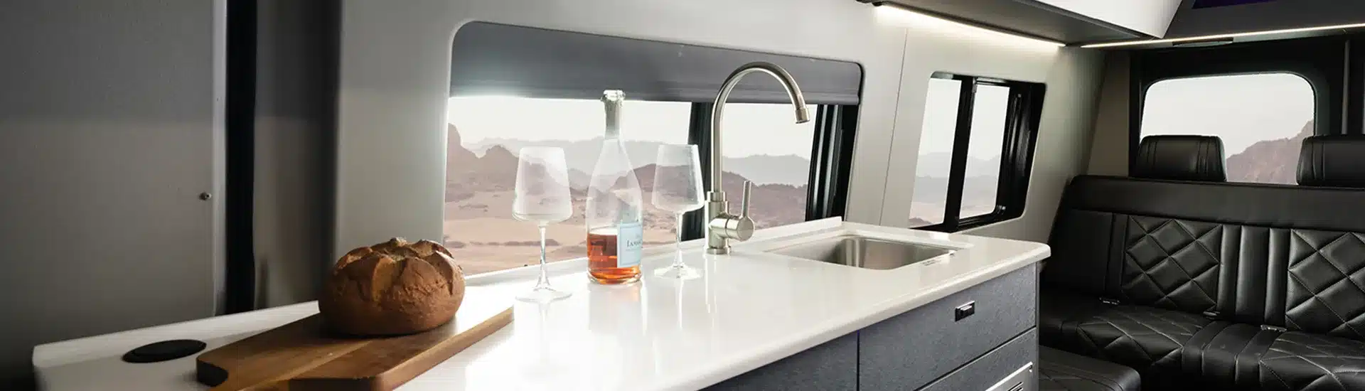Innenansicht des Entegra Insignia Executive Vans mit moderner Küchenzeile, Ledersitzbank und Panoramafenster