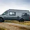 Seitenansicht eines grauen 2019 Mercedes Sprinter 170 EXT 4x4 Vans mit Offroad-Ausstattung auf einem Feldweg