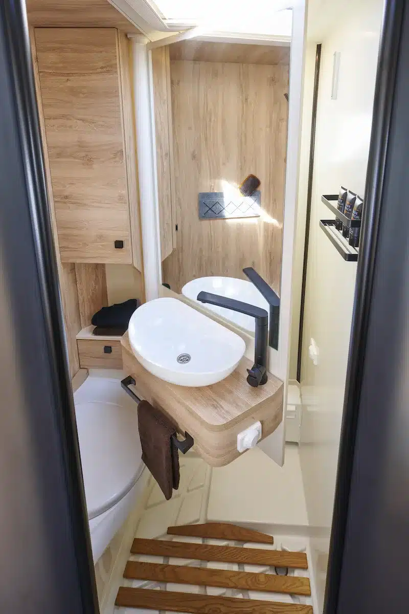 Waschraum mit Holzdekor, Schwenkwand, Waschbecken und Stauraum im Eura Mobil Xtura 4x4-Reisemobil