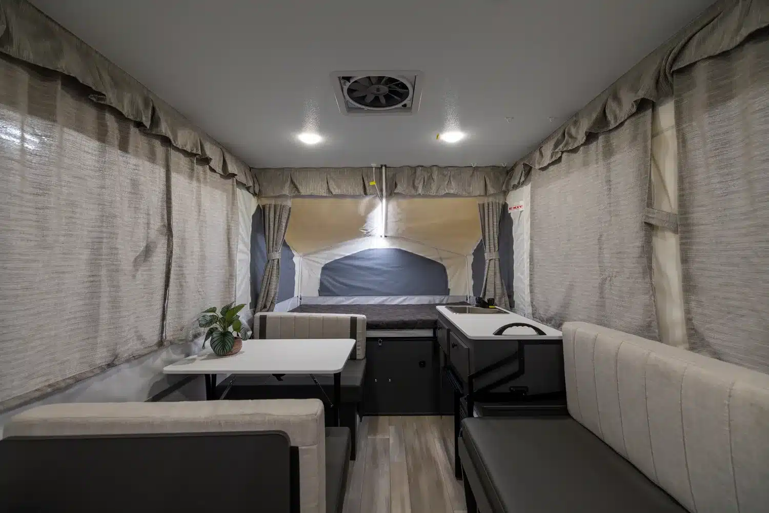 Innenansicht eines Flagstaff Tent Zeltcampers mit Sitzgruppe, Tisch, Küchenzeile und Schlafbereich