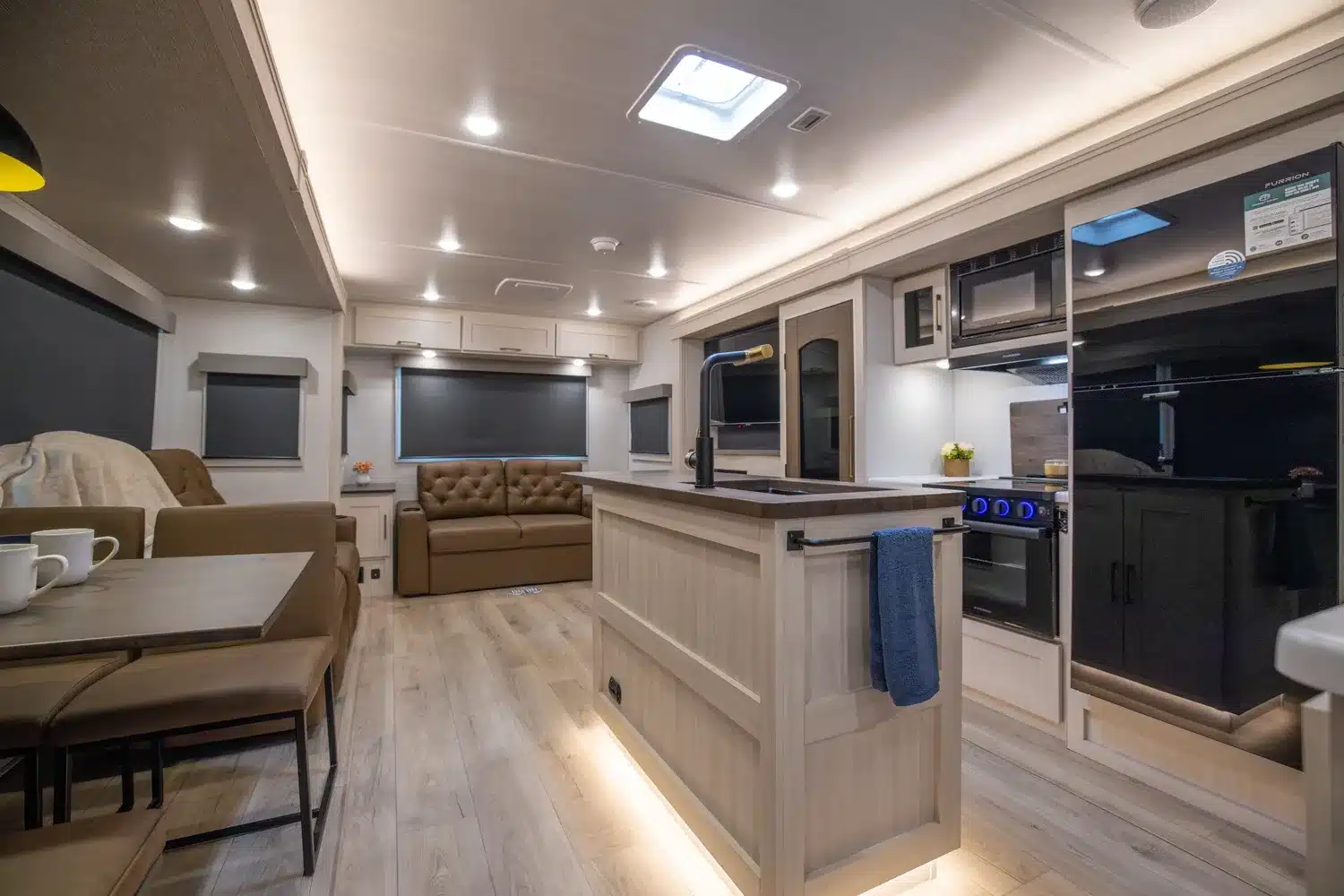 Geräumiger und moderner Innenraum eines Grand Surveyor 305RLBS Travel Trailer mit Kücheninsel, Sofa und Essbereich