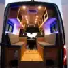 Innenansicht eines ausgebauten Elektro-Campers mit modularen Sitz- und Staumöglichkeiten, Holzverkleidung und LED-Beleuchtung