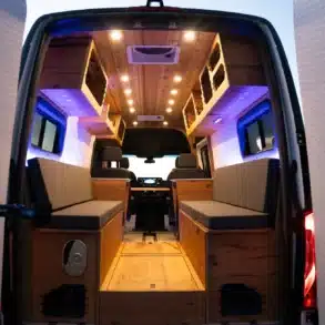 Innenansicht eines ausgebauten Elektro-Campers mit modularen Sitz- und Staumöglichkeiten, Holzverkleidung und LED-Beleuchtung
