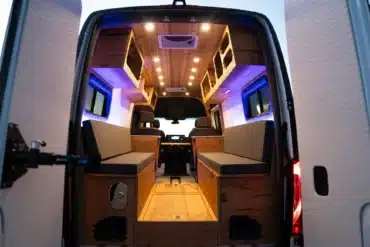 Innenansicht eines ausgebauten Elektro-Campers mit modularen Sitz- und Staumöglichkeiten, Holzverkleidung und LED-Beleuchtung