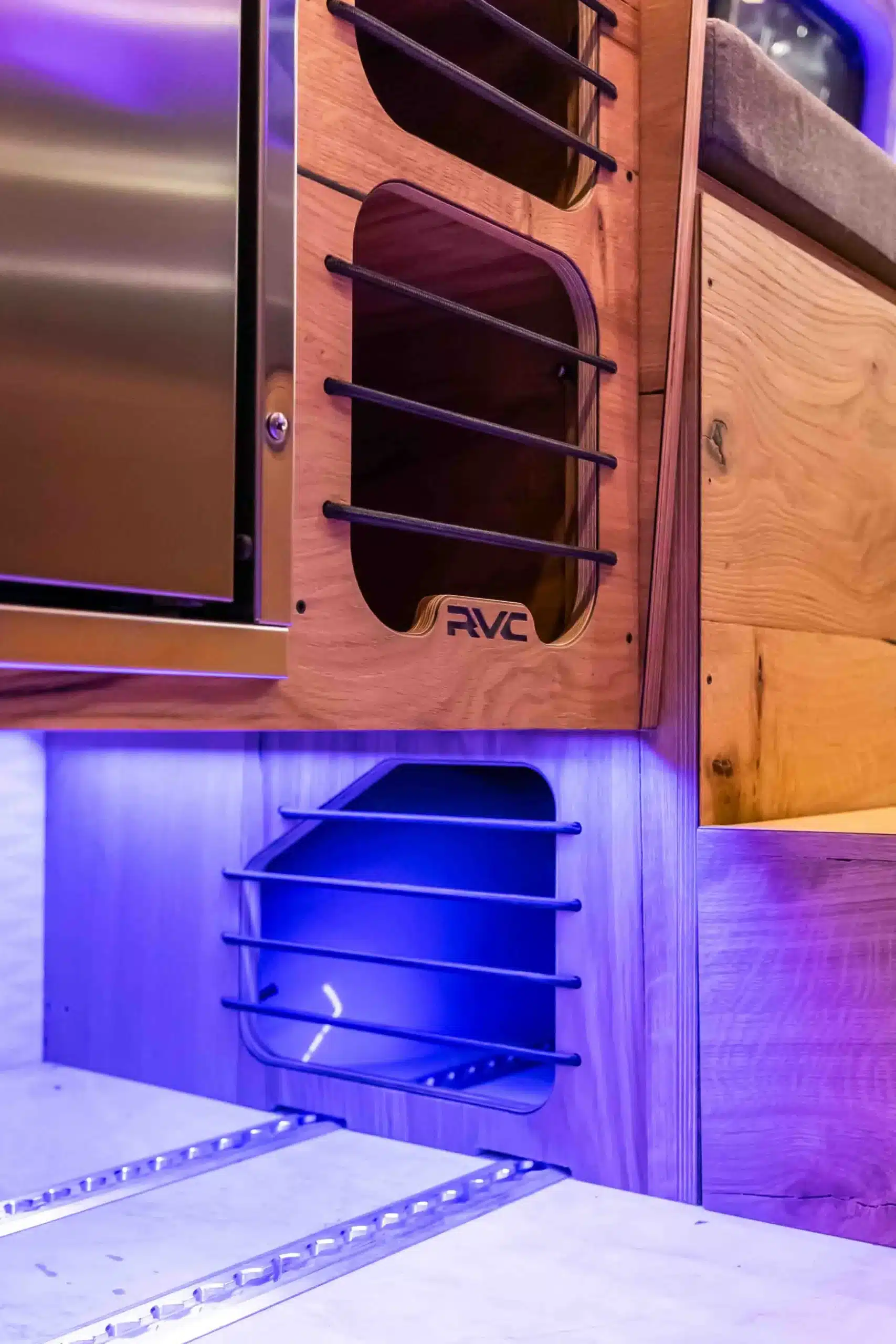 Detailaufnahme eines modularen Möbelteils mit Holzverkleidung, Metallstreben und LED-Beleuchtung im Innenraum eines GridRunner eSprinter Vans