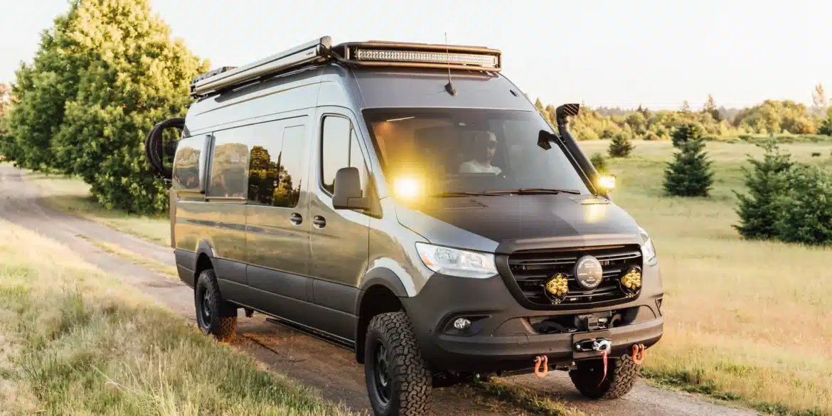 Gus 4x4 Sprinter Campervan mit Offroad-Umbau, Dachträger, Zusatzbeleuchtung und grobstolligen Reifen auf einem Feldweg