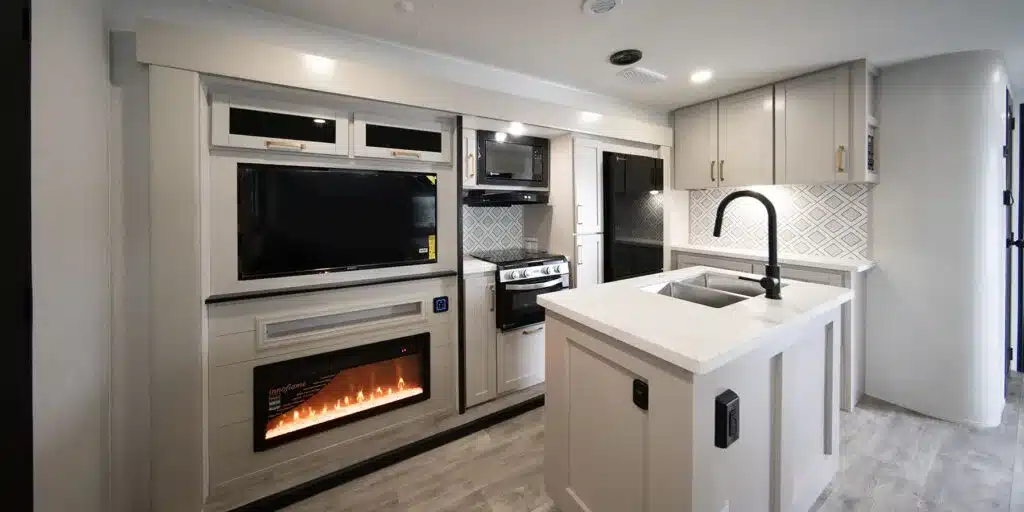 Innenansicht des Heartland 31BROK Travel Trailers mit Kücheninsel, Kamin, TV und modernen Einbauschränken