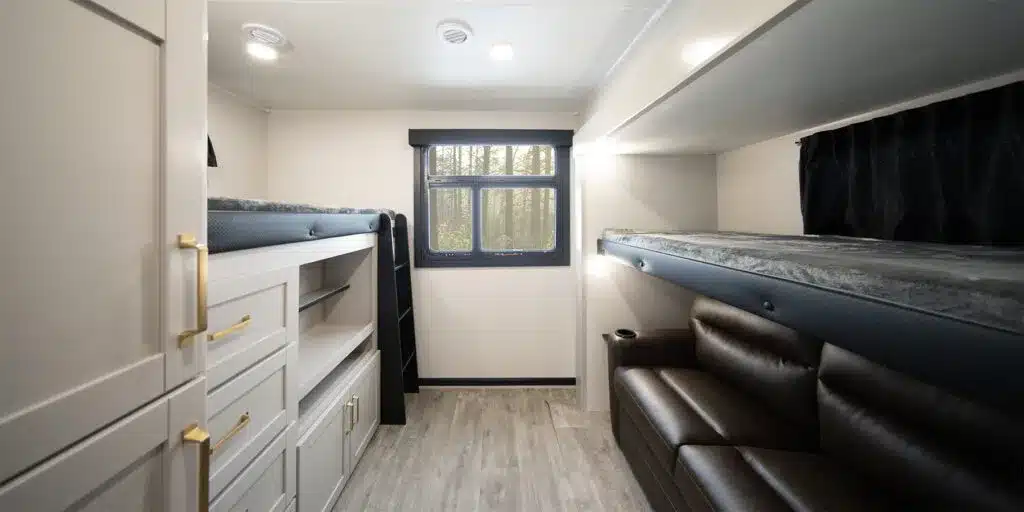 Innenansicht eines modernen Travel Trailers mit mehreren Schlafplätzen, Stauraum und Sitzgelegenheit