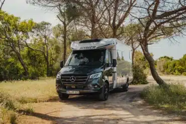 HYMER B-Klasse ModernComfort T Wohnmobil steht auf einem naturbelassenen Stellplatz im Grünen, umgeben von Bäumen