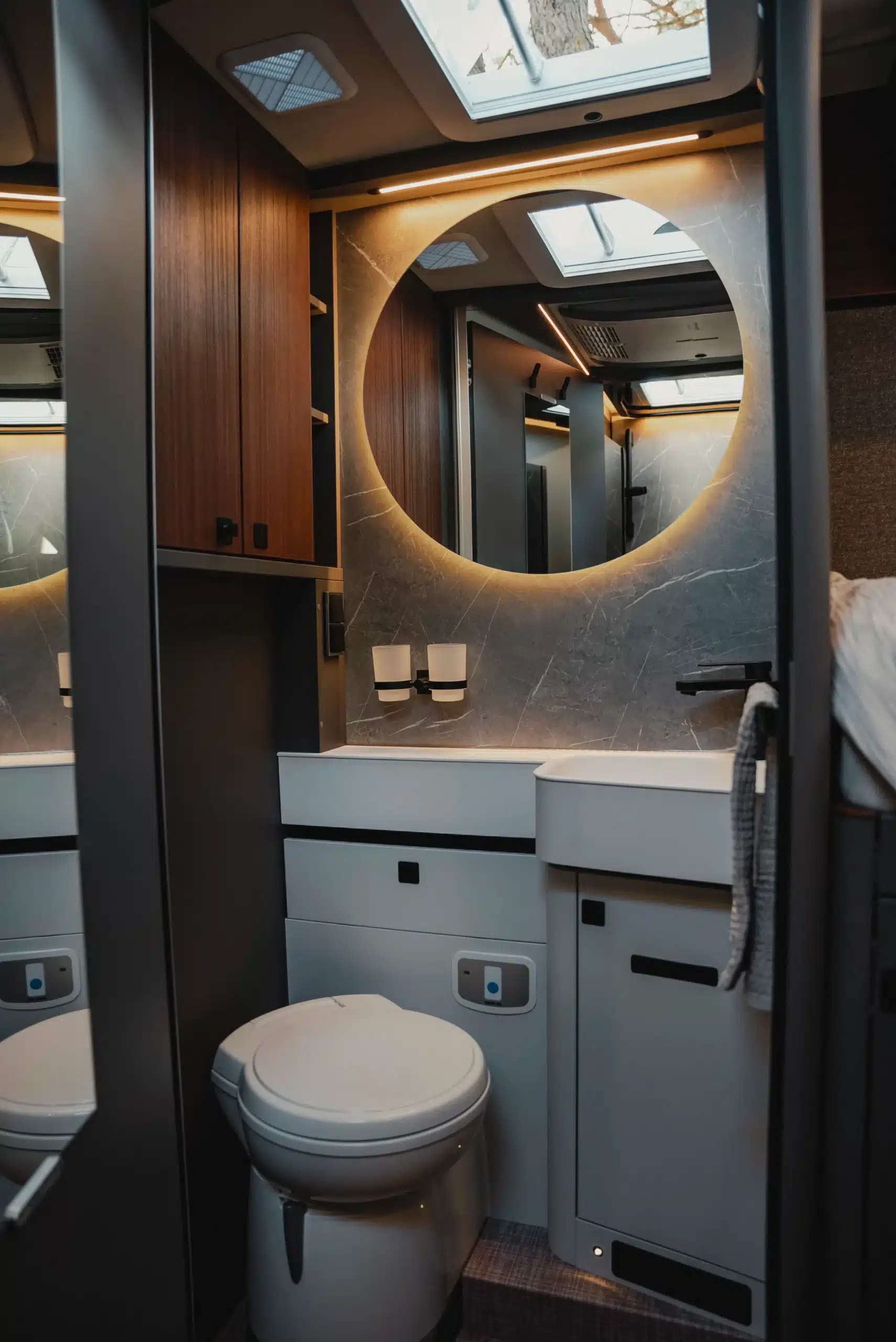Badezimmer im HYMER B-Klasse ModernComfort T mit großem Spiegel, moderner LED-Beleuchtung, Toilette und Holzschränken