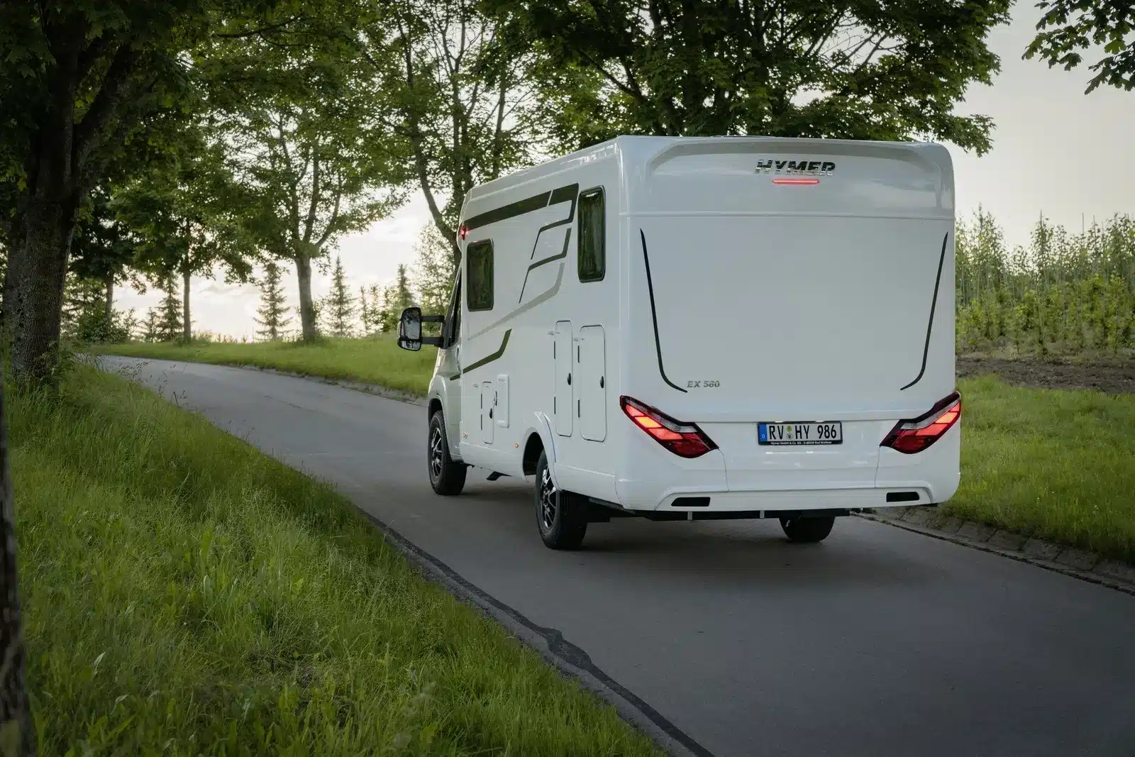 HYMER Exsis-t Pure Wohnmobil fährt auf schmaler Landstraße durch grüne Landschaft