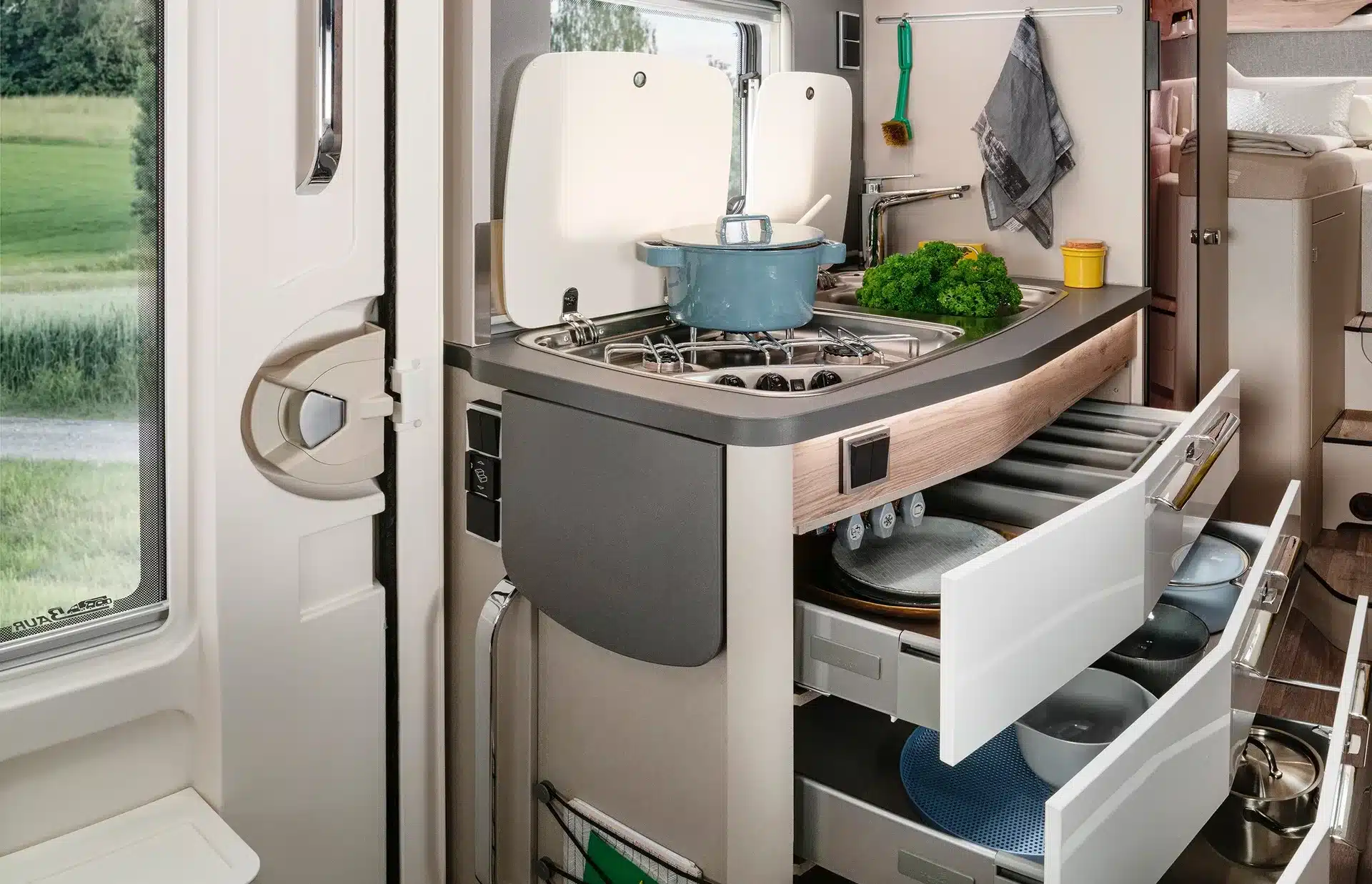 Moderne Küchenzeile mit Gasherd, Spüle und geöffneten Schubladen im HYMER Exsis-t Pure Wohnmobil