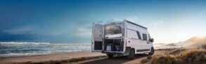 KNAUS BOXLIFE Camper Van mit geöffneten Hecktüren am Strand, Blick auf das flexible Innenraumkonzept und Stauraum