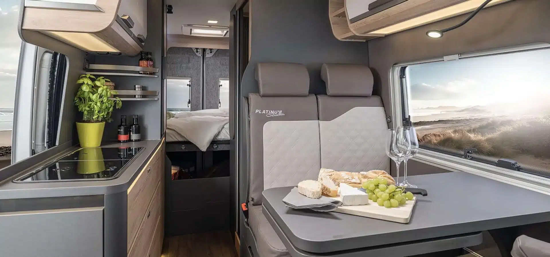 Blick in den Innenraum eines KNAUS BOXLIFE Camper Vans mit Küche, Sitzgruppe und Bett im Hintergrund