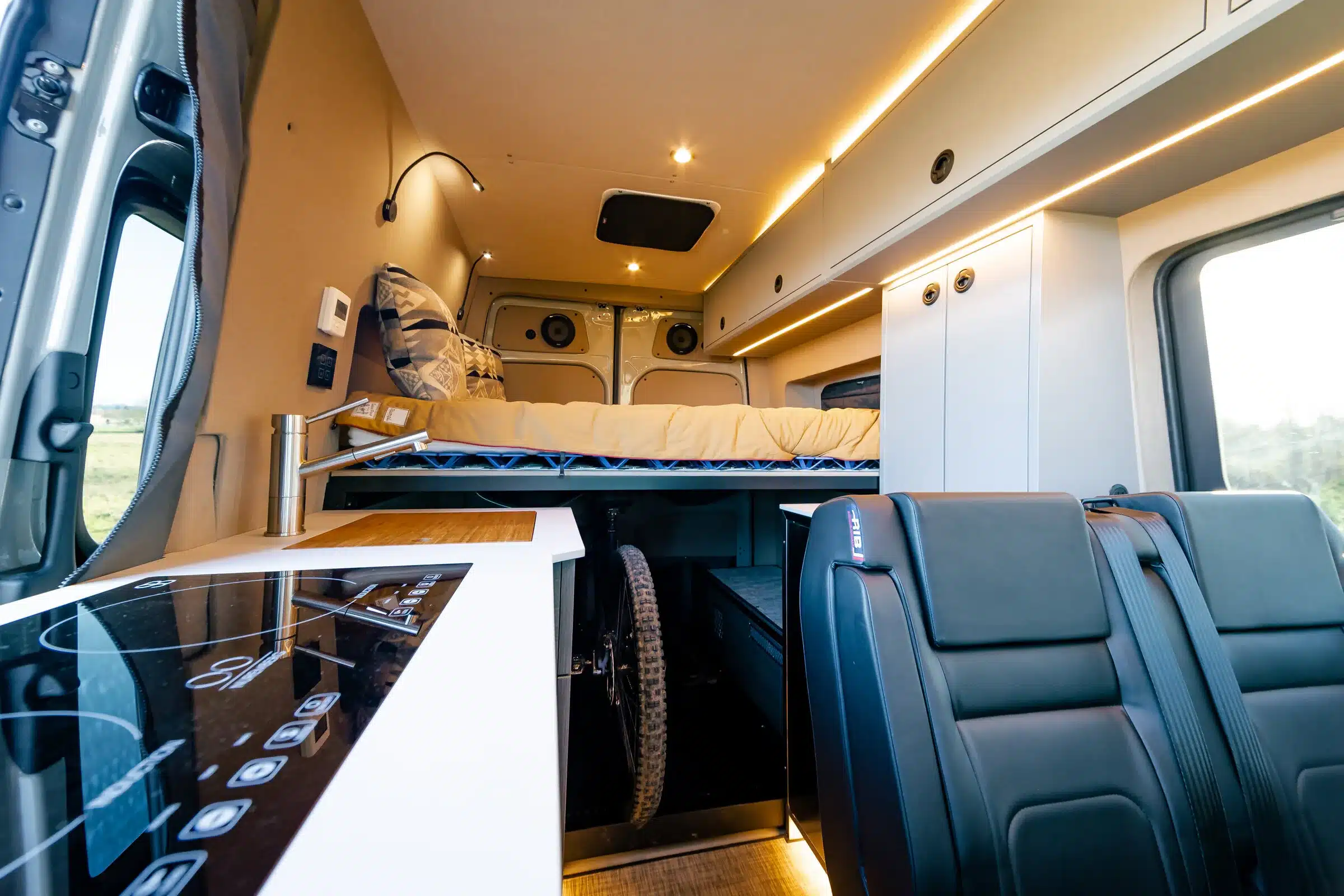 Innenraum eines ausgebauten Mercedes Sprinter 144 4x4 mit Plattformbett, Küchenzeile, Sitzbank und Stauraum für ein Fahrrad