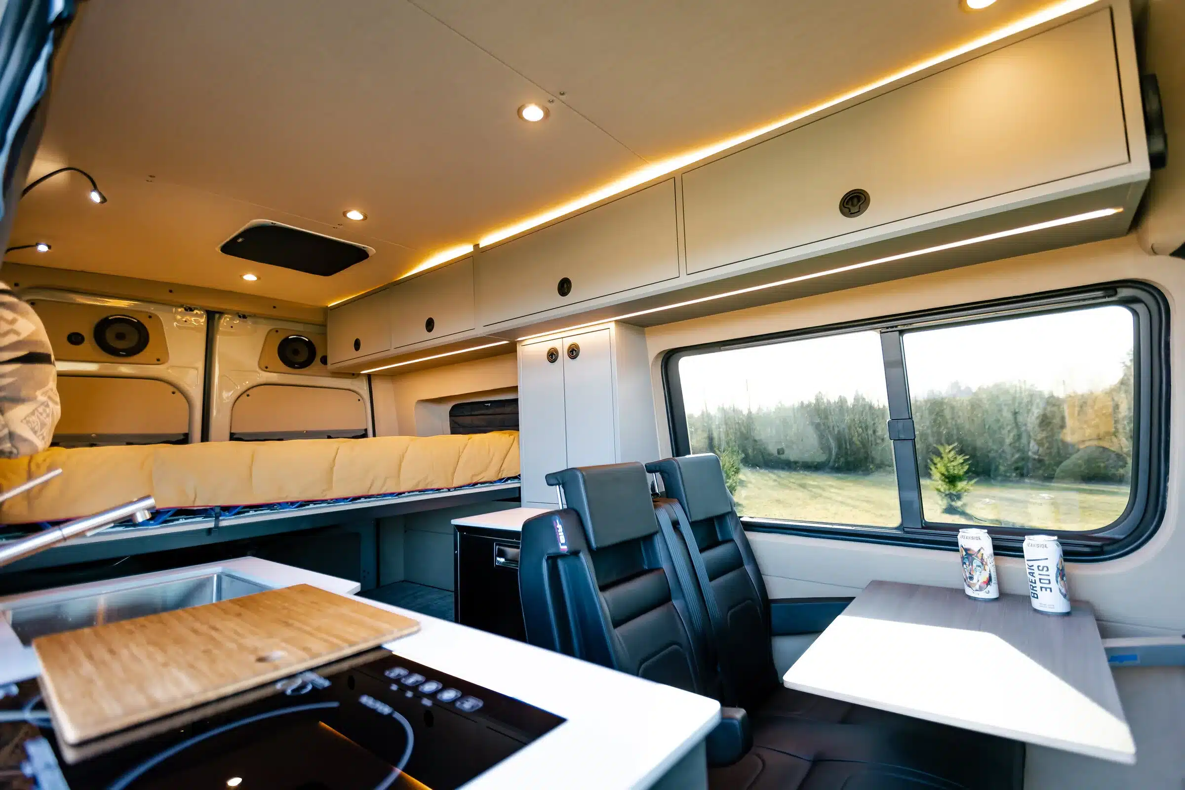 Innenansicht eines ausgebauten Mercedes Sprinter 144 4x4 Campervans mit Plattformbett, Sitzgruppe, Küchenzeile und Stauraum