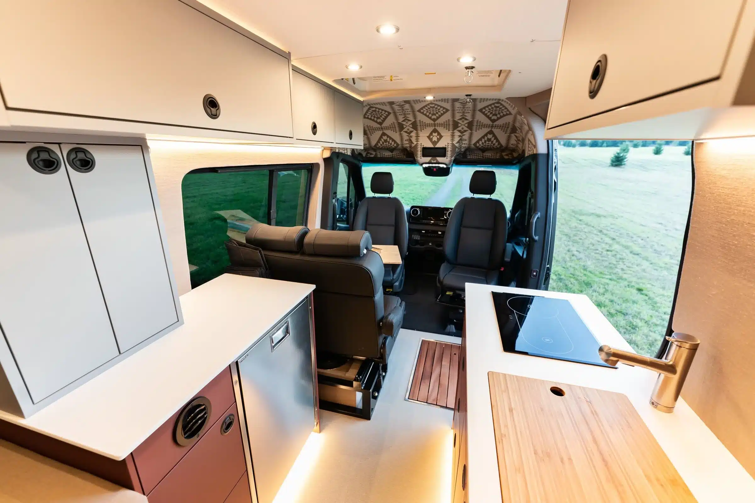 Innenansicht eines ausgebauten Mercedes Sprinter 170 4x4 mit moderner Küche, Sitzgruppe und Stauraum