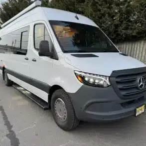 Weißer Mercedes Sprinter 170 EXT Campervan Linda Lou mit Markise, fotografiert auf einem Parkplatz.