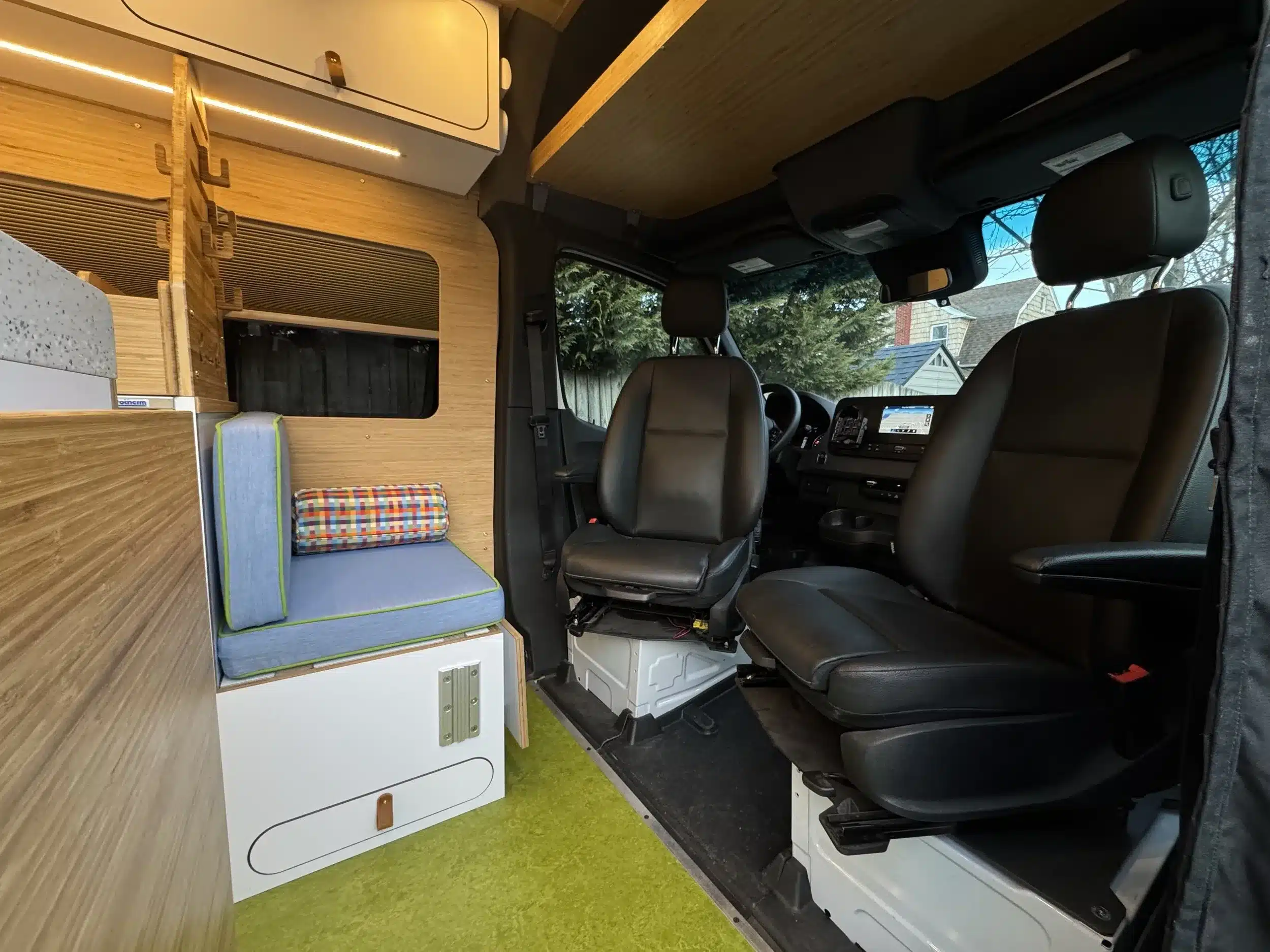 Innenansicht eines hochwertig ausgebauten Campervans mit drehbaren Fahrersitzen, Lounge-Bereich und modernen Materialien