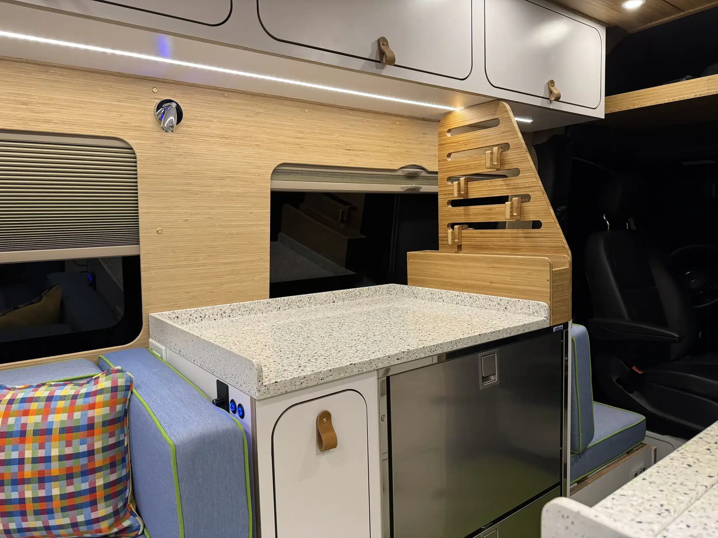 Küchenbereich eines Campervans mit Arbeitsfläche, Schränken und Sitzbank