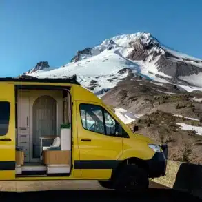 Gelber Luna Van mit offenem Schiebetür, Blick auf den stilvollen Innenraum, im Vordergrund eine Berglandschaft mit Schnee