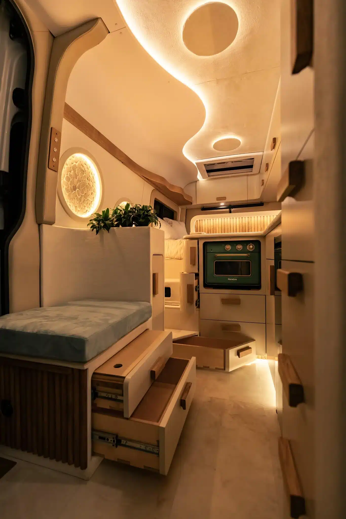 Innenansicht des Luna Van von Rogue Vans mit heller, mediterraner Gestaltung, L-förmiger Küche, Sitzbank und stimmungsvoller LED-Beleuchtung