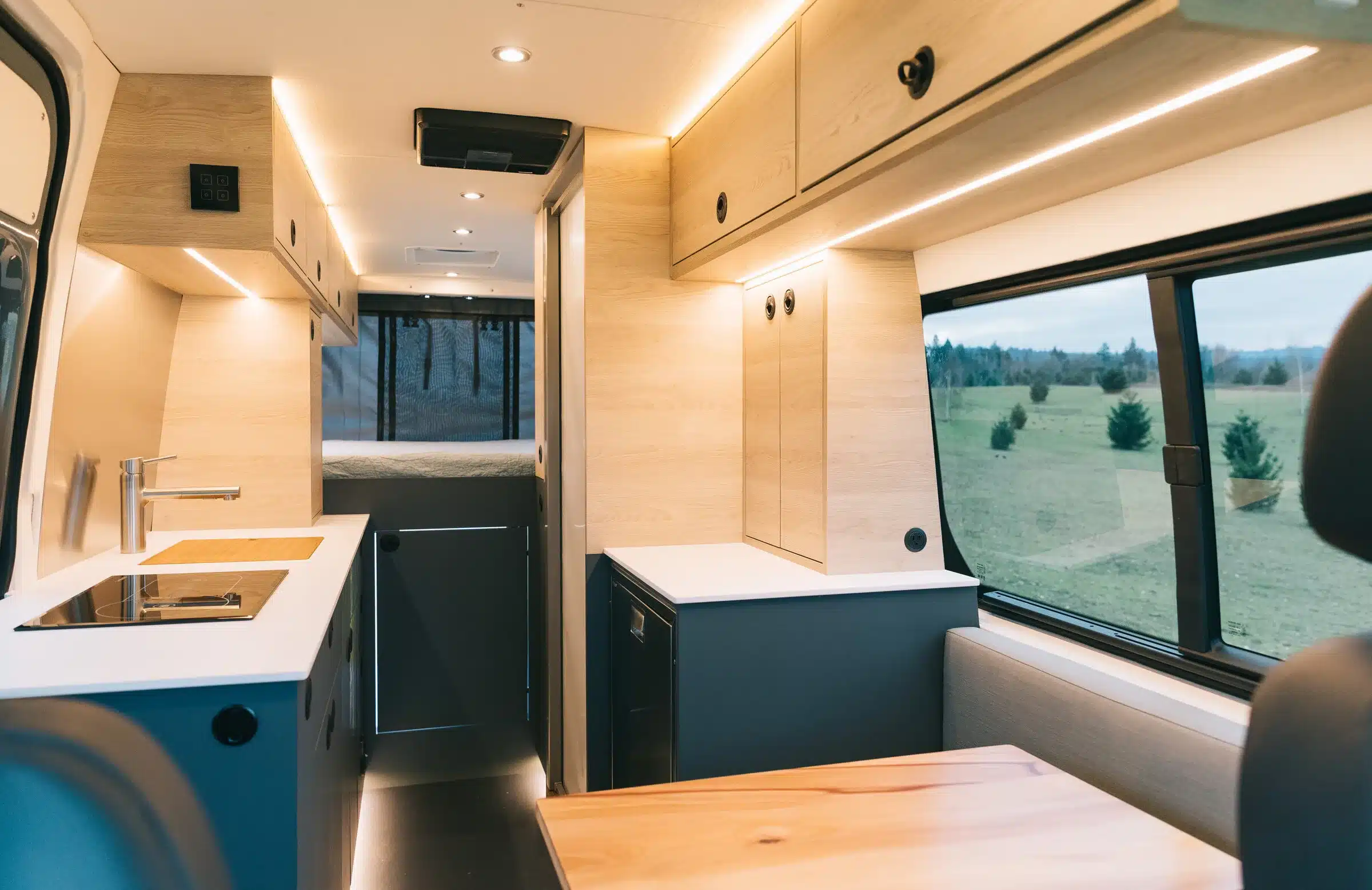 Hochwertiger Innenausbau eines Mercedes Sprinter 170 4x4 Cuddy mit Küche, Stauraum und Blick auf das Plattformbett