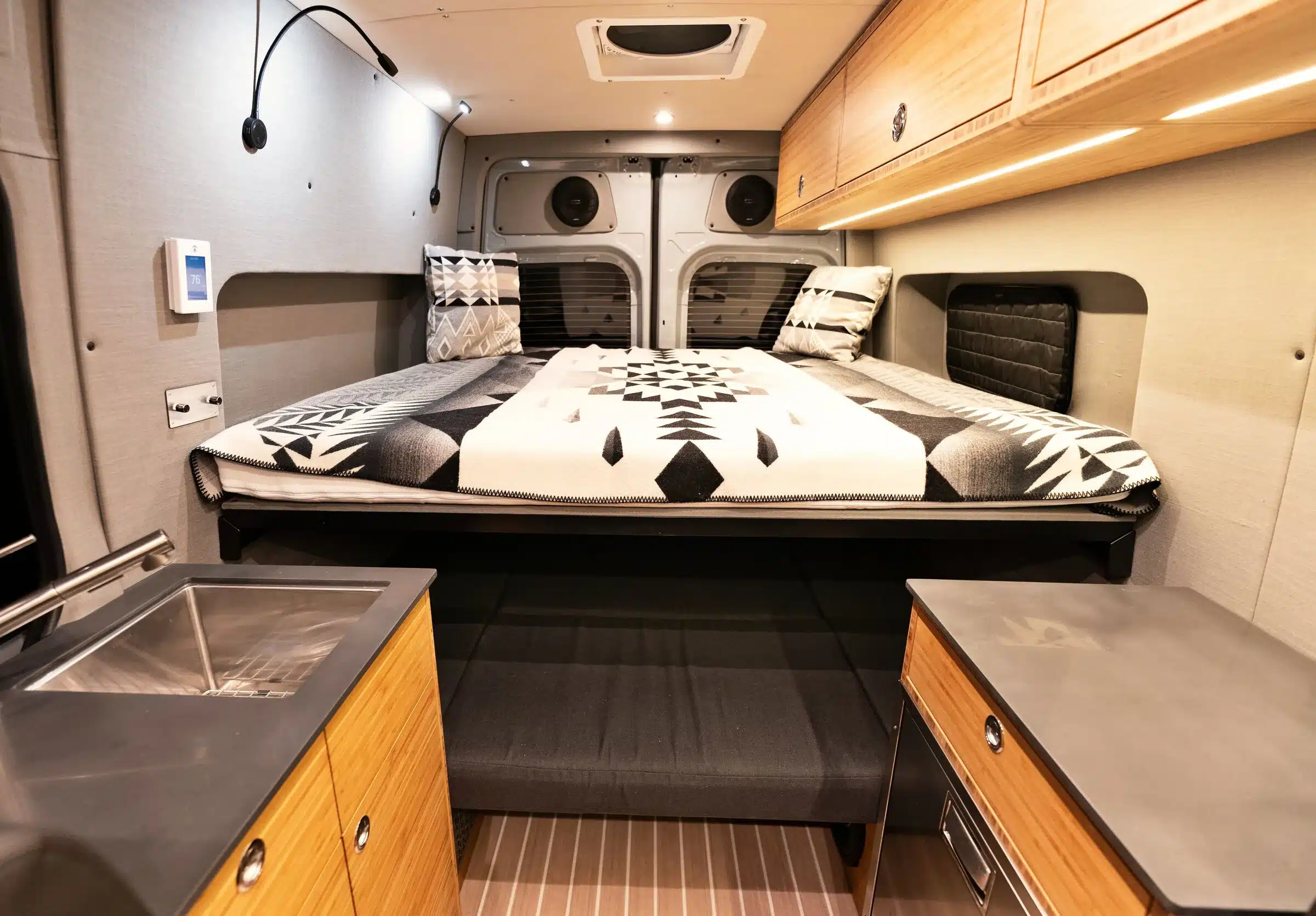 Innenansicht eines ausgebauten Mercedes Sprinter 4x4 Azure mit festem Heckbett, Küchenzeile und Stauraum