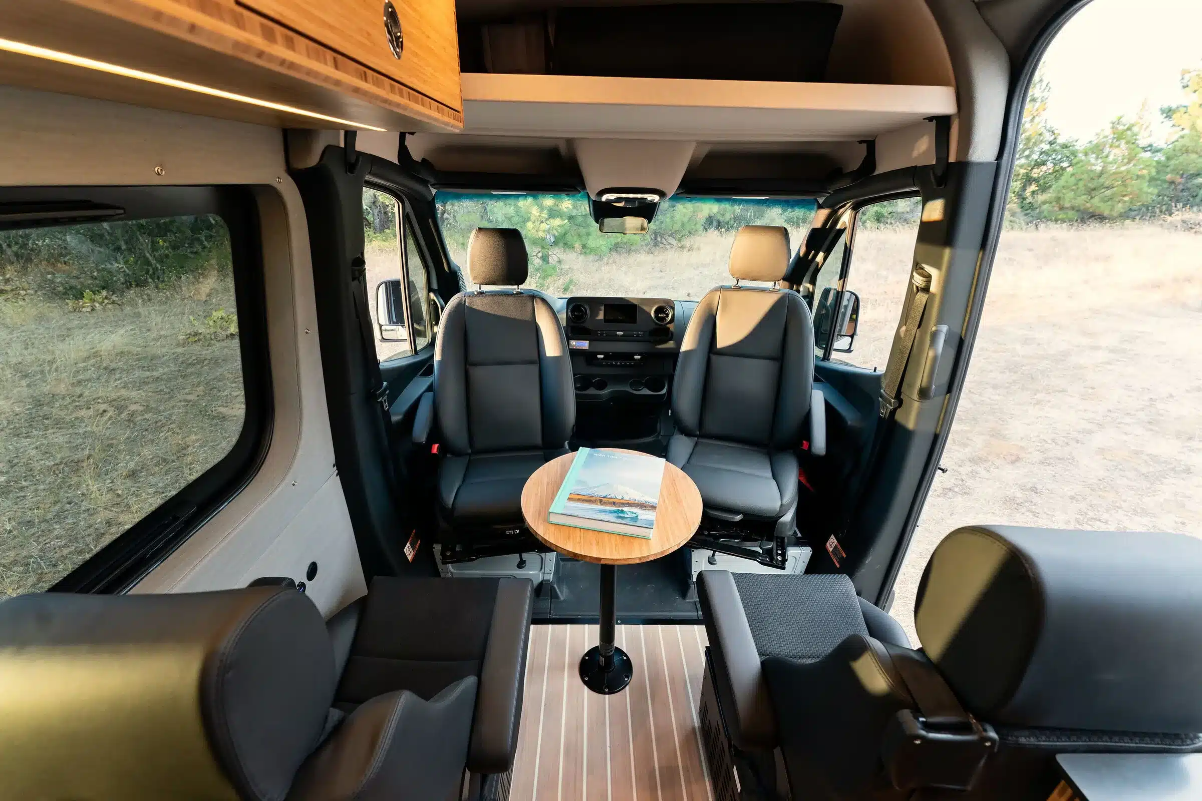 Blick in den Innenraum eines ausgebauten Mercedes Sprinter 4x4 Azure mit vier Sitzen und rundem Tisch