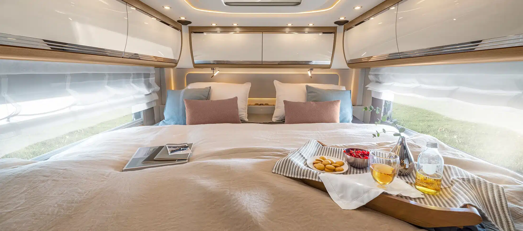 Großzügiges Bett mit Kissen und Tablett im Schlafbereich eines Morelo Empire Liner Wohnmobils