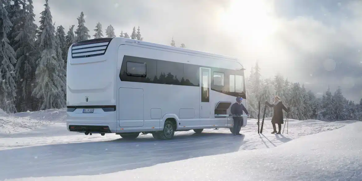 Luxuriöses Morelo Palace Wohnmobil steht im verschneiten Wald, zwei Menschen bereiten Skiausrüstung vor