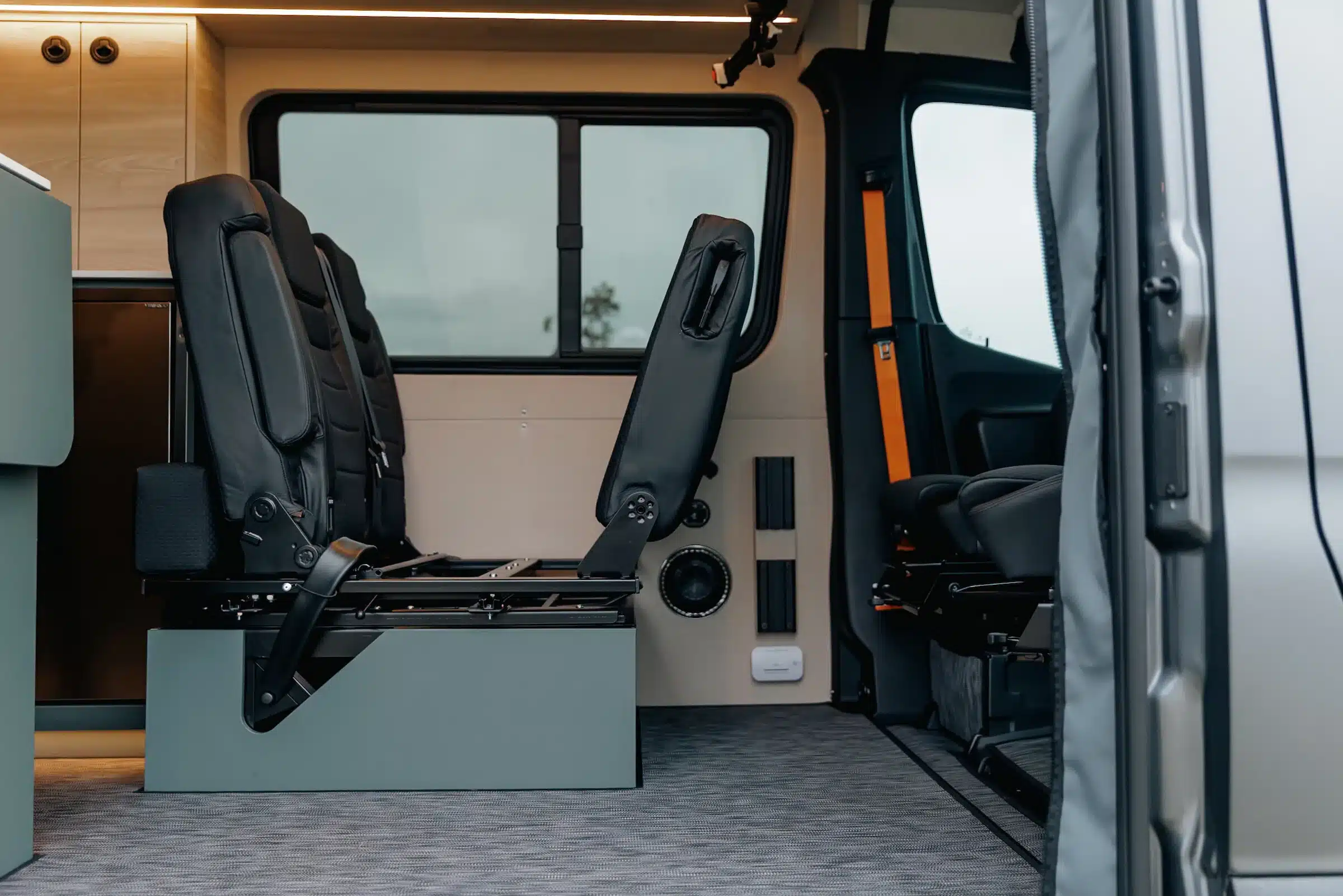 Blick auf die schwarze Sitzbank und den Innenraum eines ausgebauten Mercedes Sprinter Adventure-Vans mit Stauraum und modernen Materialien