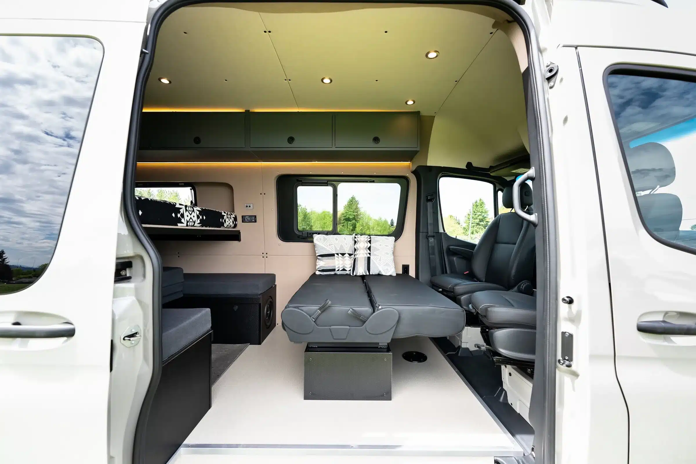 Blick in den Innenraum eines ausgebauten Mercedes Sprinter 144 High Roof mit Sitz- und Schlafbereich, Stauraum und modernen Oberflächen
