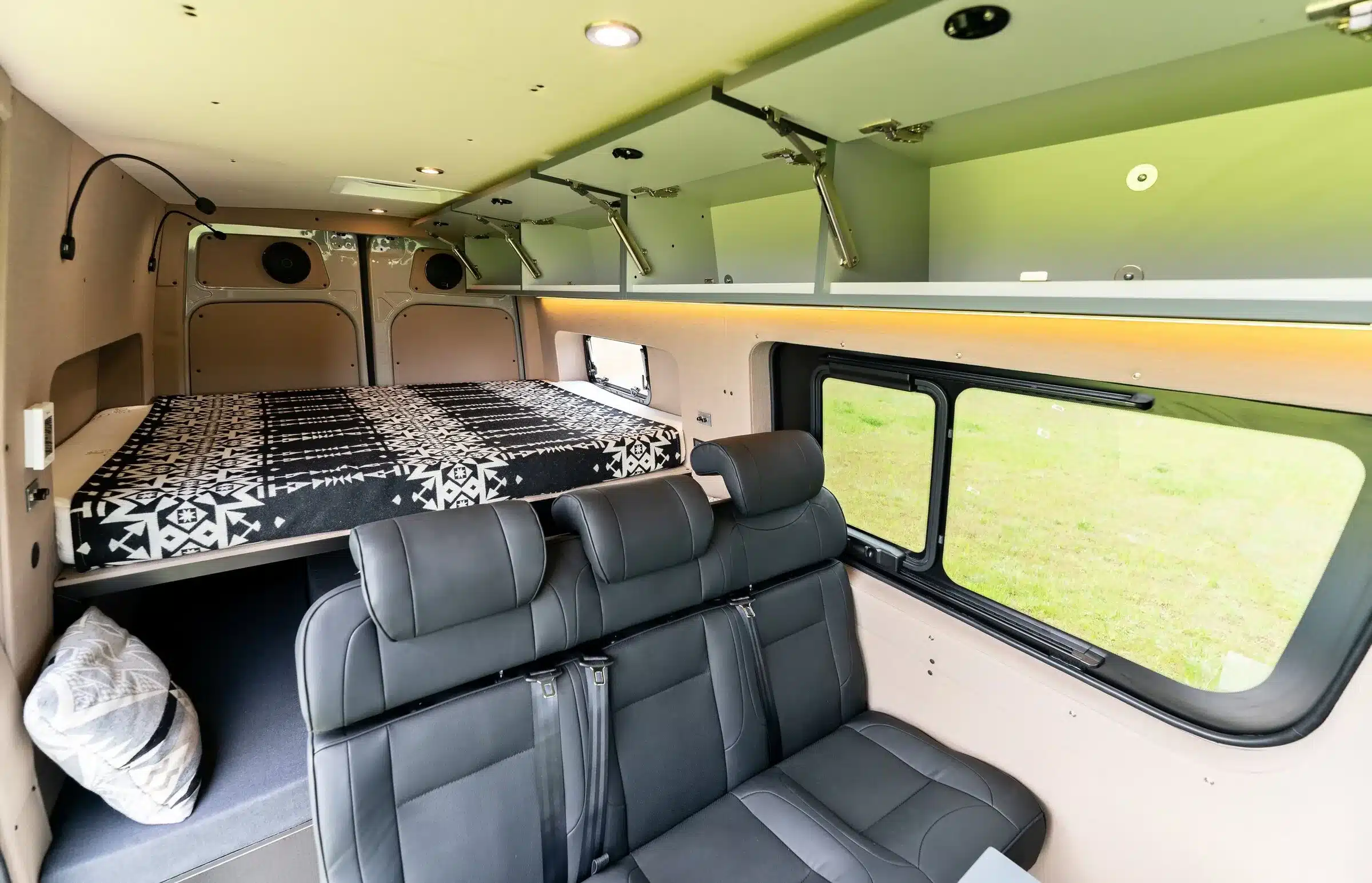 Innenansicht eines ausgebauten Mercedes Sprinter 144 High Roof mit Bett, Sitzbank und Stauraumfächern