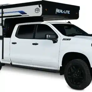 Ein weißer Pickup mit montiertem Palomino Real-Lite Truck Camper, Seitenansicht