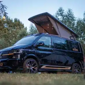 VW T6.1 Campervan Rhön Camp DER ULTIMATE mit geöffnetem Skyline Aufstelldach auf einem Campingplatz