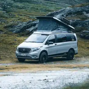 Rhön Camp The Pace Campervan auf Mercedes Vito mit geöffnetem Aufstelldach in bergiger Landschaft